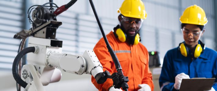engineer cooperation male and female technician maintenance control relay robot arm system welding with tablet laptop to control quality operate process work heavy industry 4.0 manufacturing factory