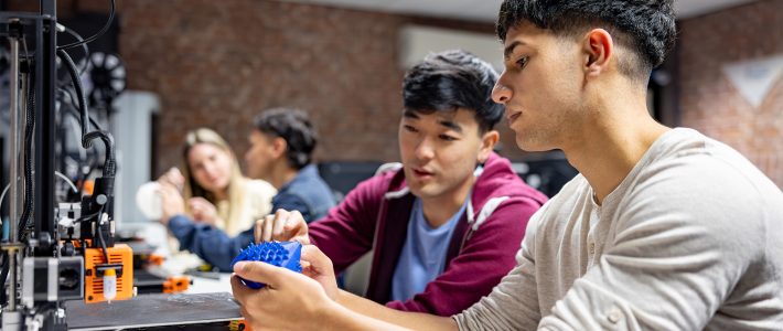 International students working with 3D printer in classroom setting.