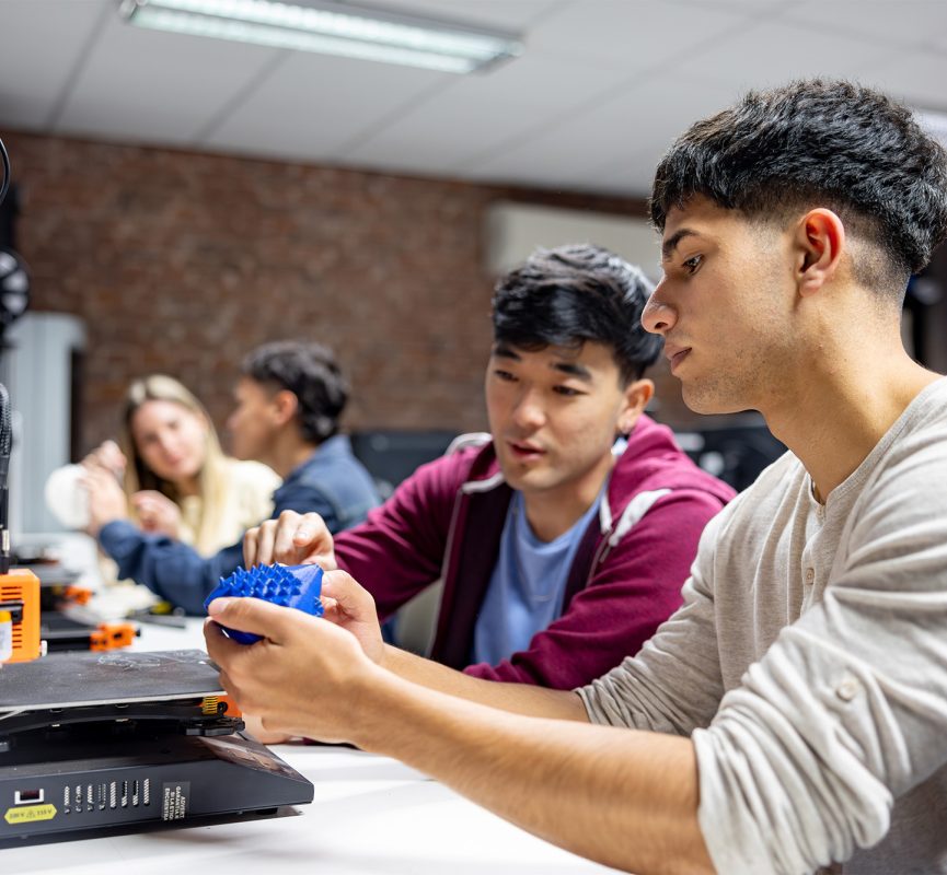 International students working with 3D printer in classroom setting.