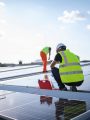 Man in safety vest working on installing solar panels in field.