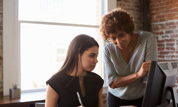 Businesswomen mentoring student On Computer In Office